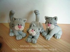 three grey cat figurines sitting on top of a wooden table next to each other