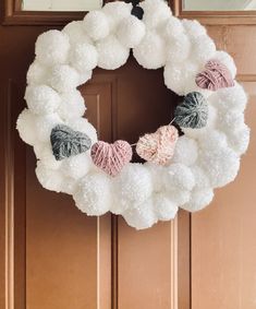 a white wreath with pom - poms hanging from the front door