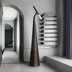 a tall metal sculpture sitting on top of a white floor next to a doorway and window