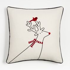 a white pillow with a red bird on it and a reindeer's head in the middle