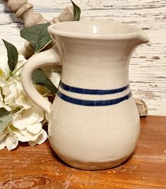 a white vase sitting on top of a wooden table