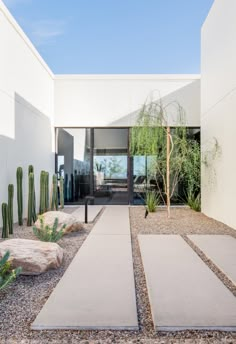 the entrance to a modern home with cactus and rocks