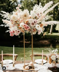 a tall vase filled with lots of flowers on top of a table next to candles