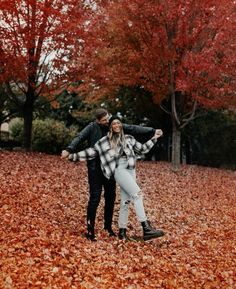 a man and woman are standing in the leaves