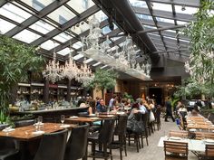 people sitting at tables in a restaurant with chandeliers hanging from the ceiling