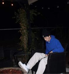 a man sitting on top of a chair next to a bowl of chili and cheese