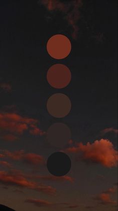 three circles are shown in the sky at night with red and black clouds behind them