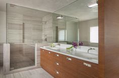 a bathroom with two sinks and a walk in shower next to a glass enclosed door