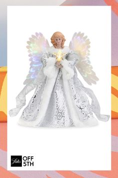 an angel figurine holding a lit candle on top of a pink and white background