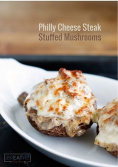 a white plate topped with three stuffed mushrooms covered in cheese and melted cheese on top