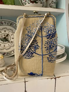 a purse sitting on top of a white shelf next to plates and bowls with blue beads