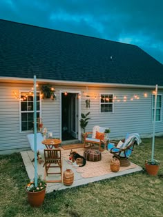 an outdoor patio with chairs and lights on the roof, next to a white house