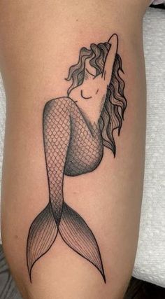 a woman's leg with a mermaid tattoo on it