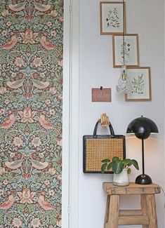 a room with wallpaper and pictures on the wall, including a chair next to a stool