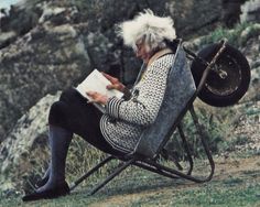 an old woman sitting in a chair reading a book with the words read books enjoy life stay awesome