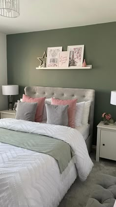 a bedroom with green walls, white bedding and pink pillows on the headboard