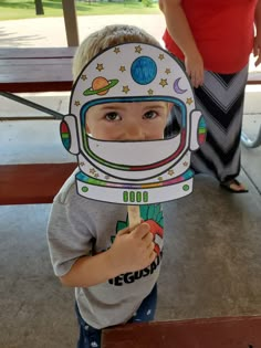 a young boy wearing an astronaut's helmet and holding a toothbrush in front of his face