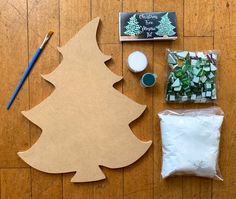 a wooden cutout of a christmas tree next to other crafting supplies on a wood floor