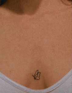 a woman's chest with a small butterfly tattoo on the left side of her breast