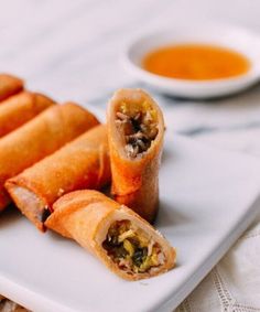 some food is on a white plate with dipping sauces in the bowl behind it