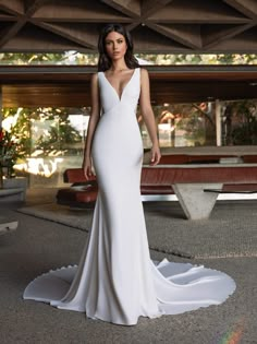 a woman in a white wedding dress standing on the ground with her hand on her hip