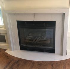 a fireplace with a white mantle and wood flooring in the middle of it is shown