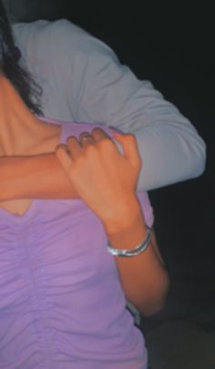 a woman in a purple shirt is holding her arm