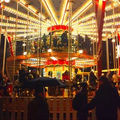 a carousel with people standing around it at night