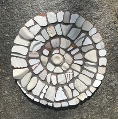 there is a circular mosaic made out of stones on the ground with no people around it