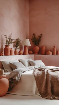 a bedroom with pink walls and vases on the shelves above the bed in front of it