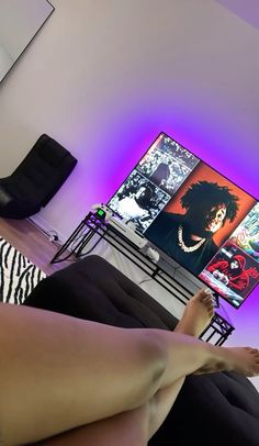 a woman laying on her stomach in front of a flat screen tv with purple lighting