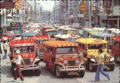 a busy city street filled with lots of cars and people walking on the side walk