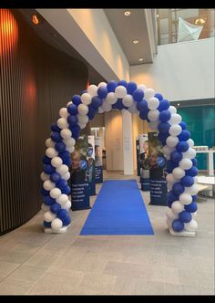 an arch made out of balloons in the middle of a hallway with blue carpeting