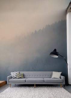 a living room with a gray couch and white rugs on the floor next to a large wall painting