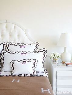 a white bed sitting next to a night stand with two lamps on top of it