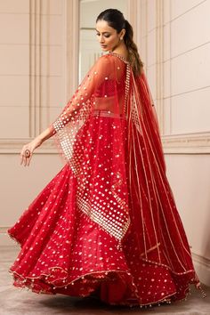 Red asymmetric organza brocade lehenga with an under-layer of chevron borders. Paired with a textured bustier with fringe embellishment. Comes with a sheer cape with square-cut gota embroidery and gota-lined wings extended in the back.
Component: 3
Pattern: Embroidered
Type Of Work: Geometric
Neckline: Cape: Round
Sleeve Type: Cape: Draped Sleeves
Fabric: Silk organza brocade
Color: Red
Other Details: 
Draped lehenga
Tassel detail
Gota work
Asymmetric cape
Occasion: Destination Wedding - Aza Fas Red Floor-length Choli With Gota Work, Floor-length Red Choli With Gota Work, Red Organza Dress For Navratri, Red Cutdana Choli For Party, Party Red Choli With Cutdana Details, Red Sharara With Sheer Dupatta In Chanderi, Red Saree With Sheer Dupatta For Reception, Red Organza Floor-length Saree, Floor-length Red Organza Saree