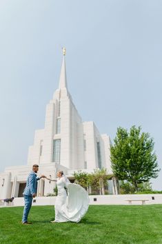 a man and woman standing in front of a large white building with a cross on it