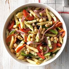 a white bowl filled with pasta salad on top of a wooden table