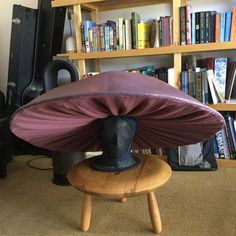 a hat sitting on top of a wooden stool in front of a bookshelf