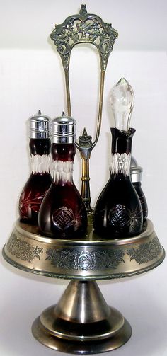 three bottles of liquor are sitting on top of a silver tray with an ornate handle