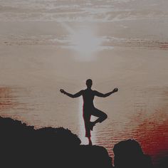 a man standing on top of a rock next to the ocean with his arms wide open