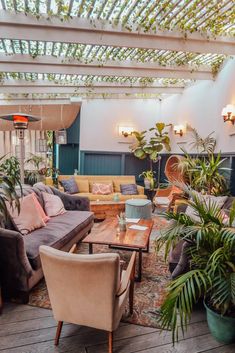 a living room filled with lots of furniture and potted plants on top of it