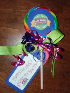 there is a lollipop on the table next to a card and some ribbons