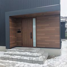 two wooden doors in front of a building with snow on the ground and steps leading up to it