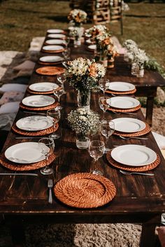 a long wooden table set with plates and place settings for an outdoor dinner party or gathering