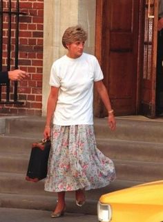 the woman is walking down the street with her suitcase in hand and wearing a white t - shirt