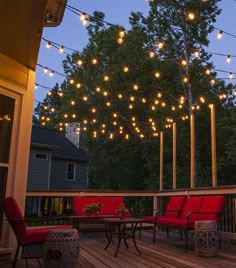 an outdoor deck with string lights and red chairs