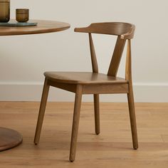 a wooden chair sitting in front of a table with a cup on top of it