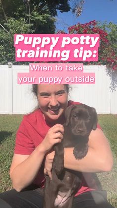 a woman sitting on the grass holding a puppy in her lap with a sign that says puppy potty training tip when to take your puppy outside