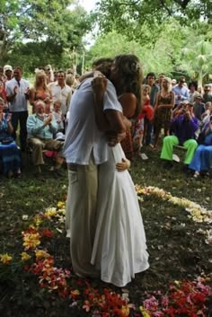 a bride and groom kissing in front of an outdoor wedding ceremony with many people watching